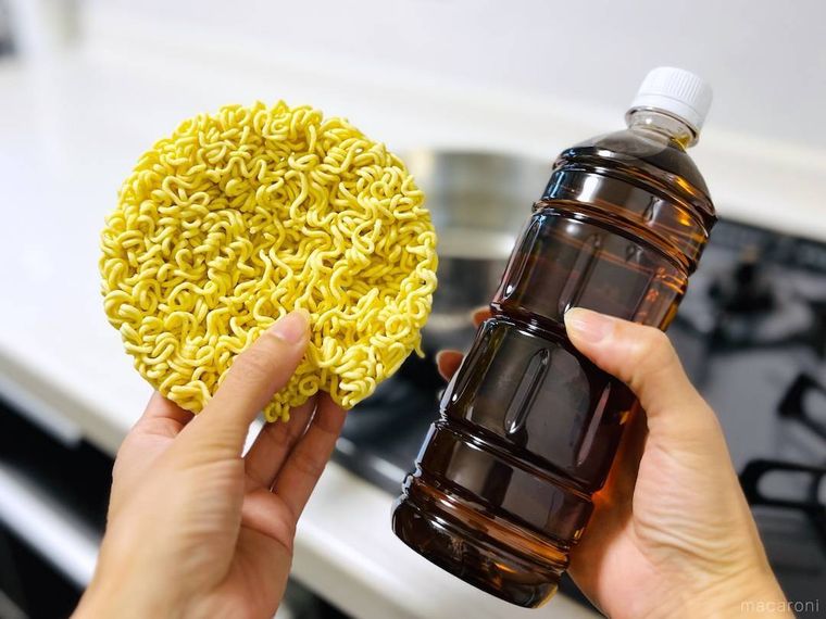インスタントラーメンと麦茶のペットボトルを両手で持っている様子