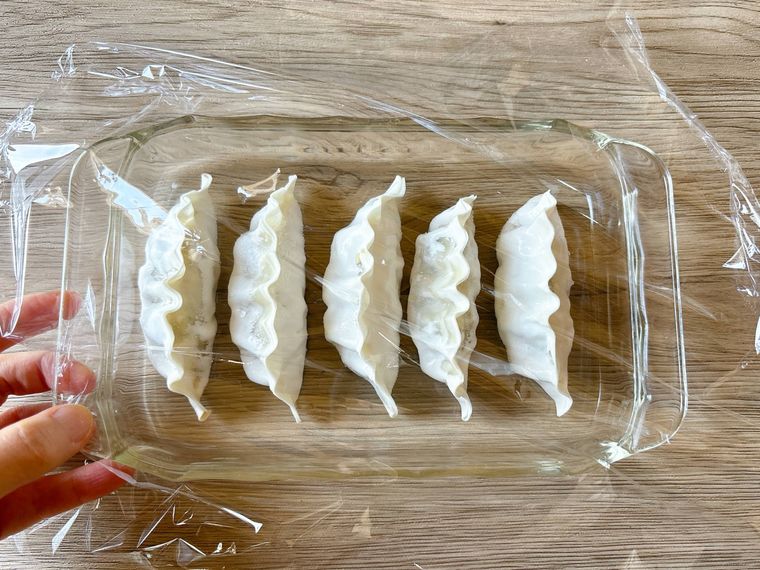 耐熱皿に入った冷凍餃子にラップをふんわりかけたもの