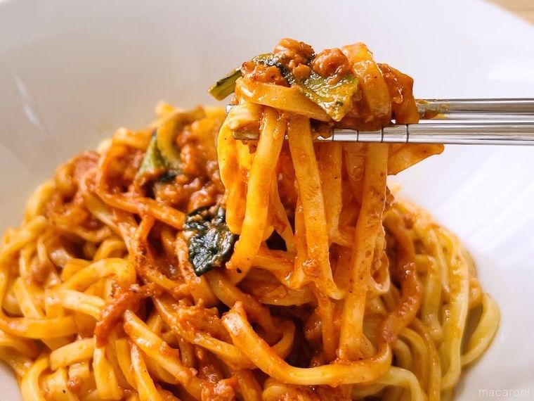 ファミリーマートのもちっと麺と濃厚だれの汁なし担々麺を箸で持ち上げている様子