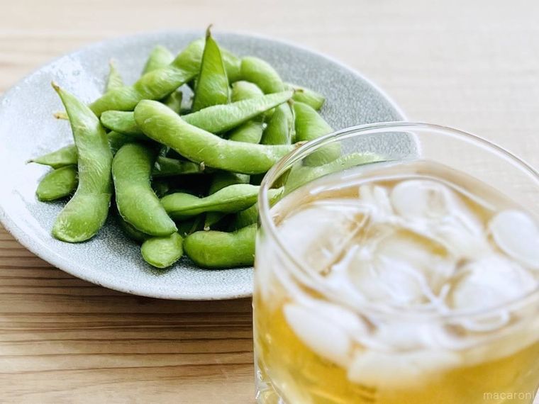 皿に盛ったレンジで手軽に塩味枝豆と、お酒が入ったグラス