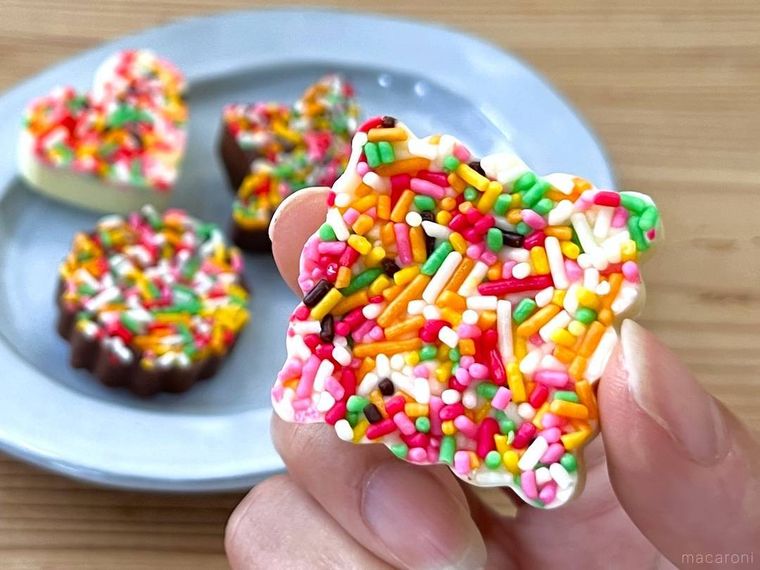 チョコスプレーでデコレーションをしたチョコレートを指でつまんでいる様子