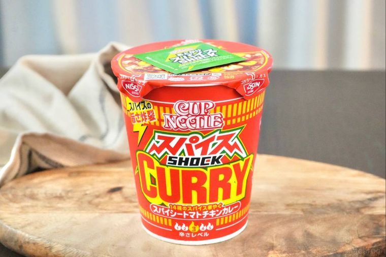 木のカッティングボードにのった赤いパッケージのスパイスカレーヌードル