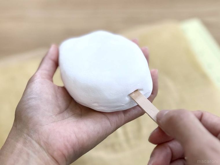 スポンジに貼り付けた粘土にアイスの棒を差し込んでいる様子