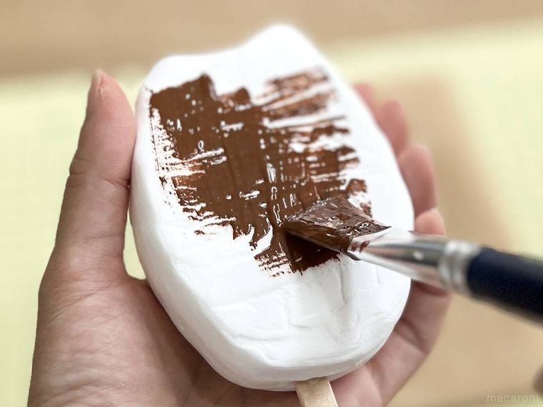 粘土に茶色い絵の具を塗っている様子