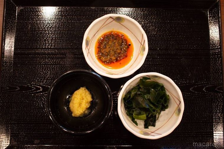 小皿に盛られた丸亀製麺の無料トッピングしび辛ラー油おろししょうがわかめがおぼんに並んでいる