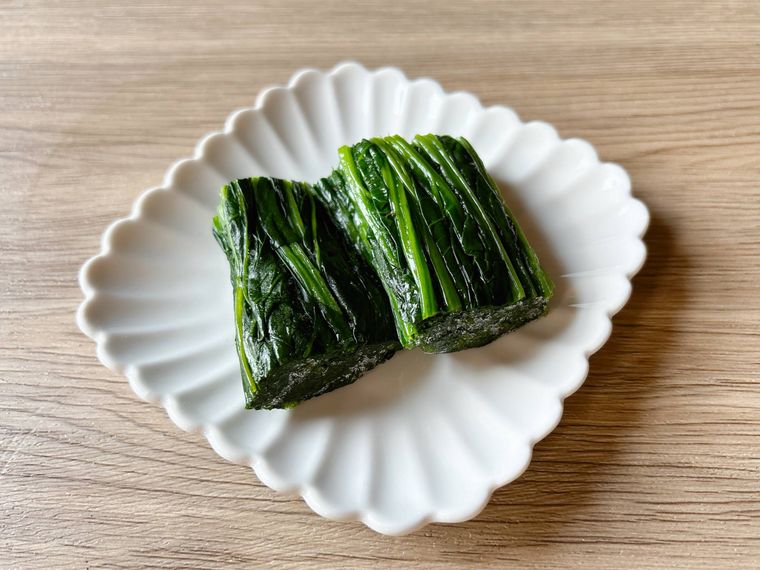 皿におかれた下ゆでして冷凍したほうれん草を解凍したもの