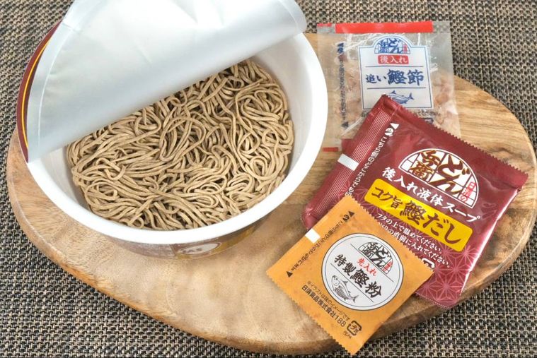 木のカッティングボードにのったカップそばと別添えの調味料