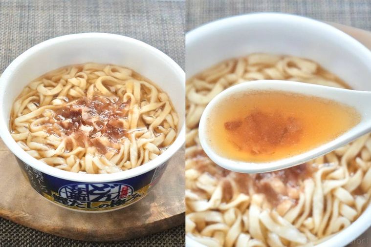 木のカッティングボードにのったカップうどんと白いれんげでつゆをすくう様子