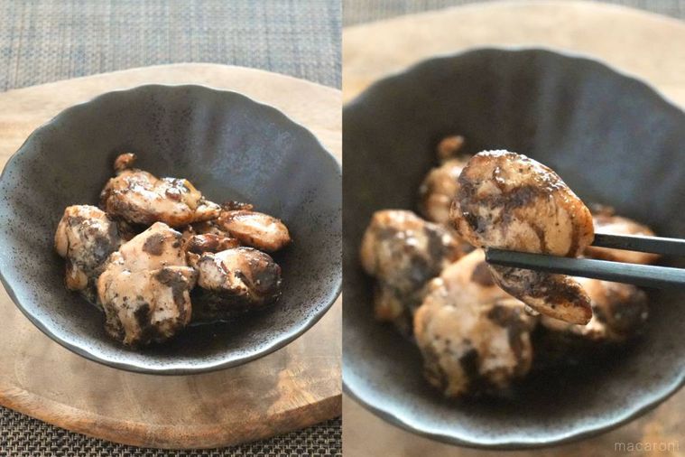 木のカッティングボードにのった黒い器に盛られたふりそでの炭火焼きを黒い箸で持ち上げる様子