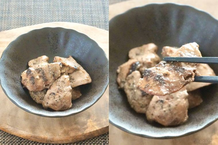 木のカッティングボードにのった黒い器に盛られたレバーの炭火焼きを黒い箸で持ち上げる様子