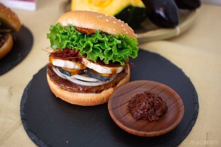フレッシュネスバーガー生七味香る 蓮根と南瓜の黒酢あんバーガーと生七味が黒いプレートの上に並んでいる
