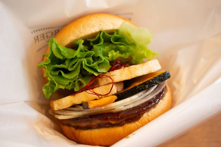 フレッシュネスバーガー生七味香る 蓮根と南瓜の黒酢あんバーガーを手で持っている様子