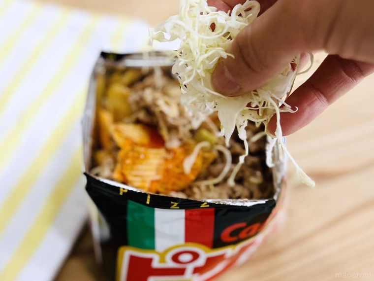 ケバブ風ピザポテトに千切りキャベツを加えようとしている様子