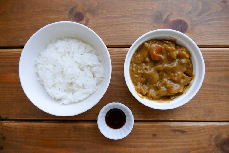 ご飯、カレー、しょうゆが並ぶ木製テーブル