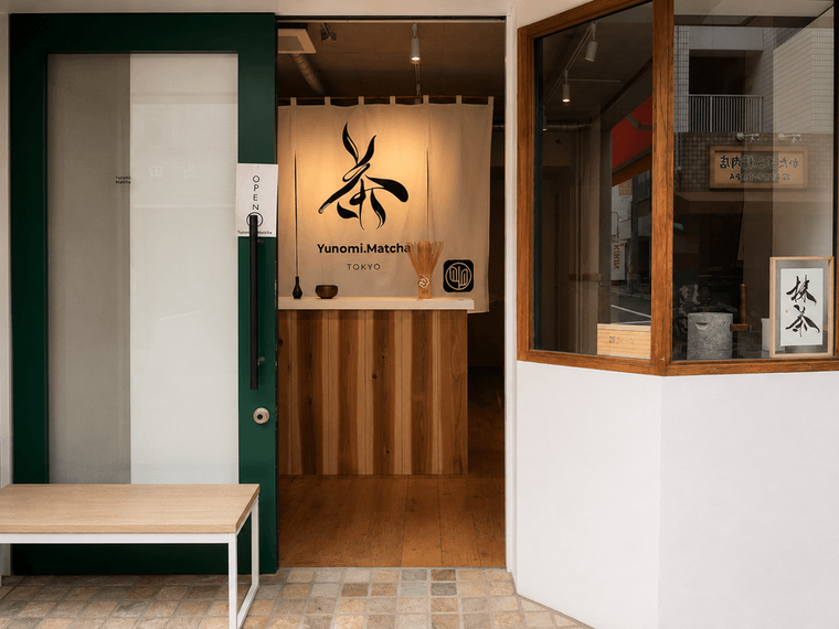 白い壁に木の扉、のれんに茶と書かれている外観