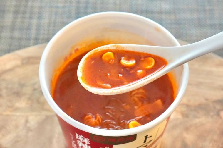 木のカッティングボードにのったカップ麻辣湯を白いれんげで食べる様子