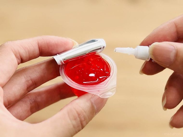 スライムを詰めたゼリーの空き容器に接着剤を付けようとしている様子