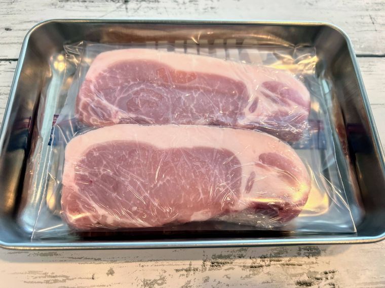 フリーザーバッグに入れてアルミトレイの上に置き、冷凍保存の準備をされた豚厚切り肉