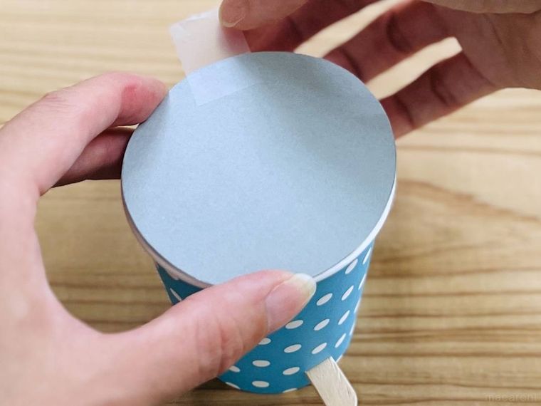 紙コップの上部に画用紙を貼り付けている様子