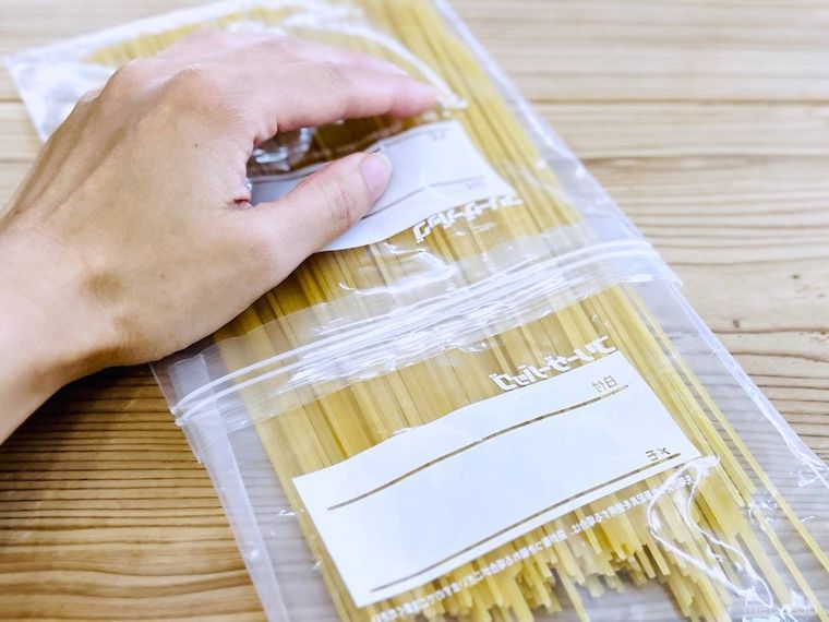 パスタが入ったジップ付き保存袋を手で押さえている様子
