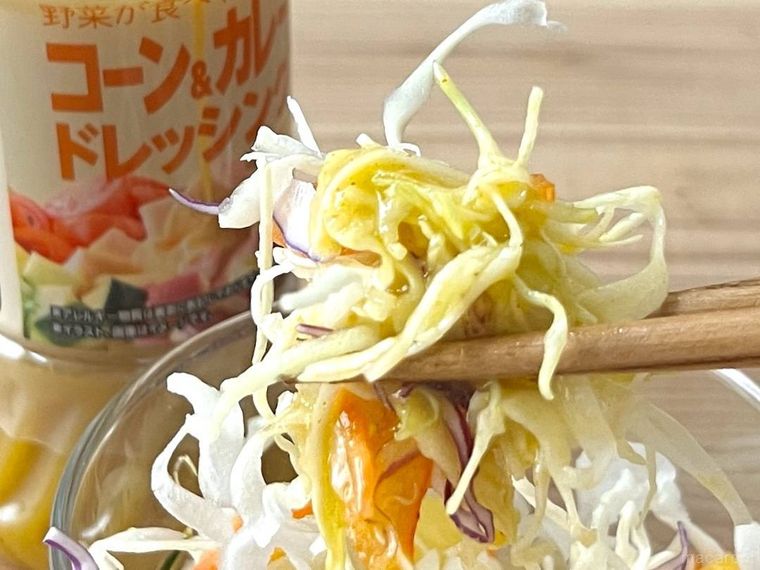 コーンカレードレッシングがかかったサラダを、箸で持ち上げている様子