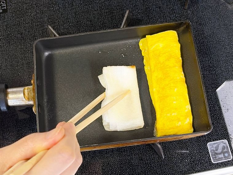 巻いた卵を卵焼き器の奥へ移動して油を塗る様子