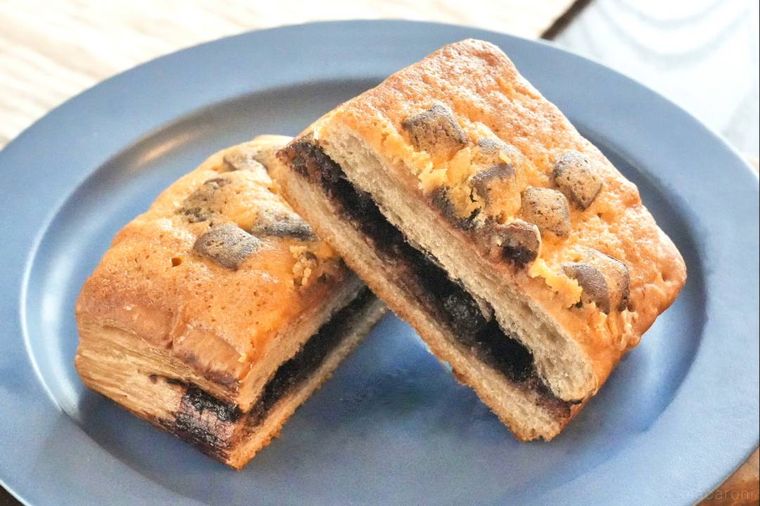 木のカッティングボードと青い皿にのったチョコレートデニッシュの断面