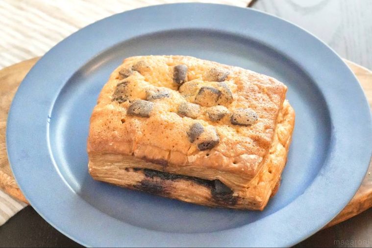 木のカッティングボードと青い皿にのったチョコレートデニッシュ