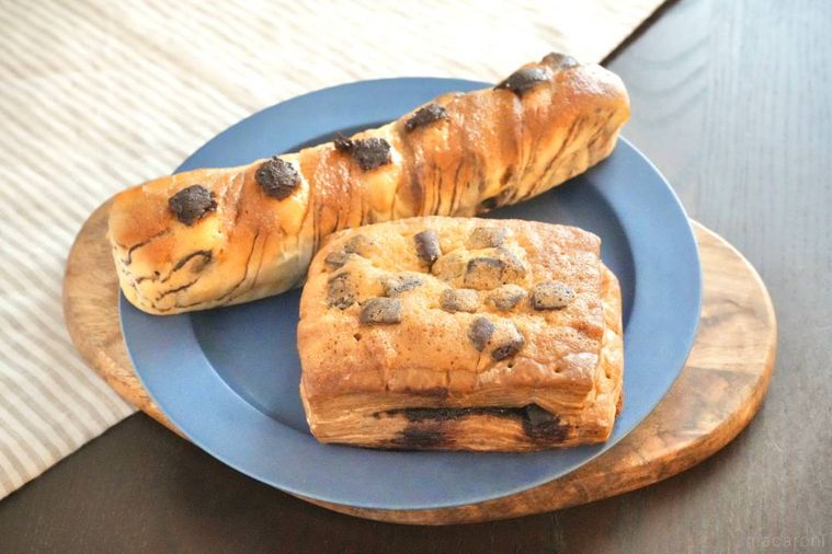 ストライプの布と青い皿にのったチョコデニッシュとスティックパン