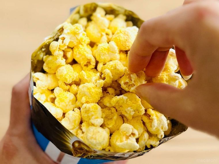 コーンポタージュの素をかけたポップコーンをつまんでいる様子