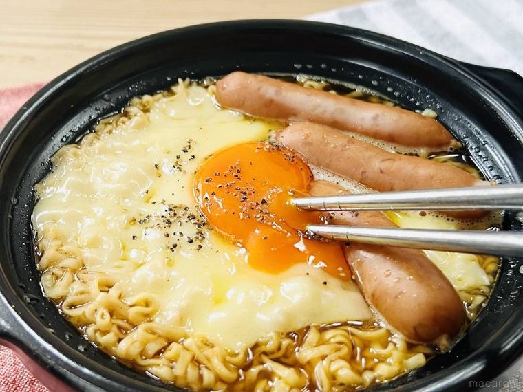 ウインナーとチーズがのったチキンラーメンの卵黄を崩している様子