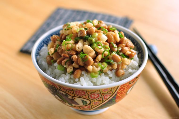 茶碗に盛り付けられたごはんの上に小口ねぎと天かすを入れた納豆がのっている
