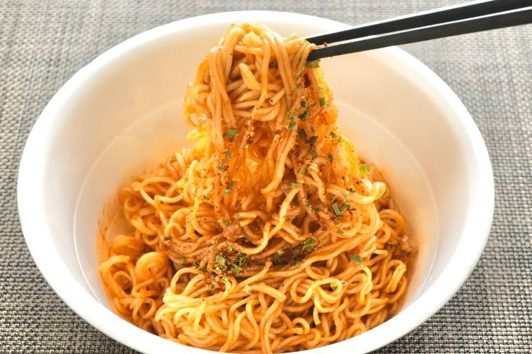 カップ麺の汁なし四川麻辣麺を黒い箸で食べる様子