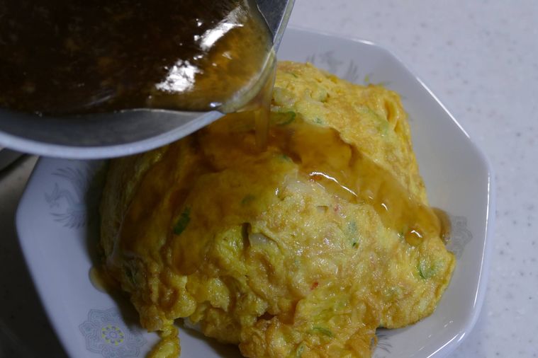 ごはんに卵をのせ、あんをかける様子