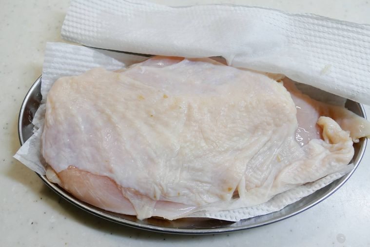 鶏むね肉表面の水分をキッチンペーパーで拭く様子
