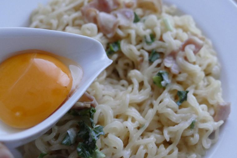 カルボナーラ風コムタンラーメンに卵黄をトッピングする様子