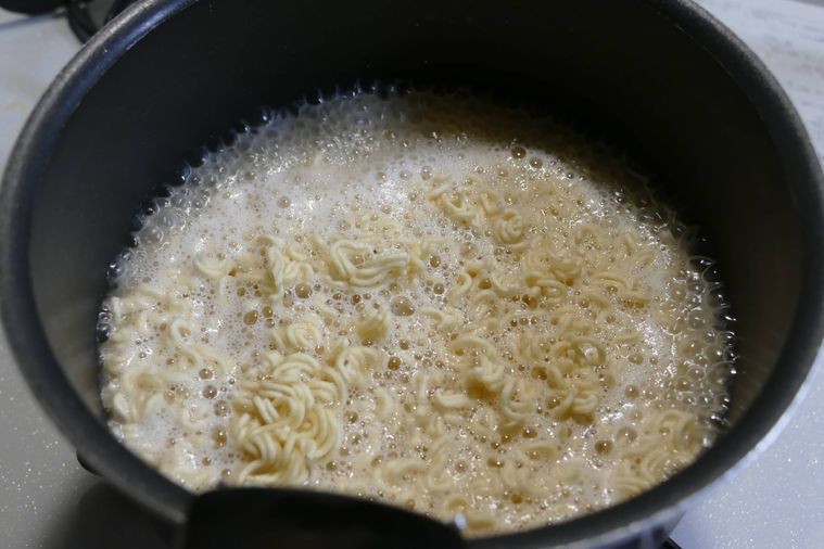 砕いた麺を煮込む様子