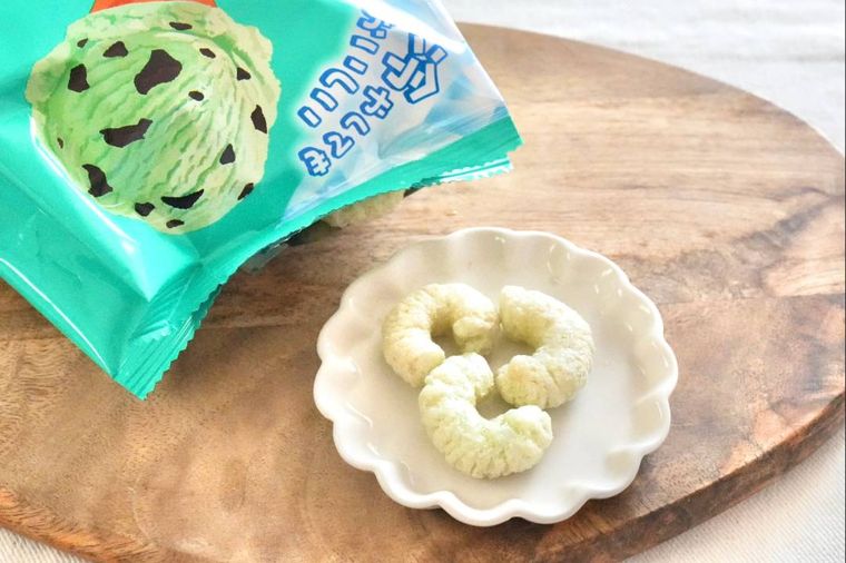 木のカッティングボードと白い小皿にのったチョコミント味のキャラメルコーンとミント色のパッケージ