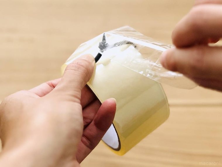 結束バンドを取り付けた透明テープを手で切っている様子