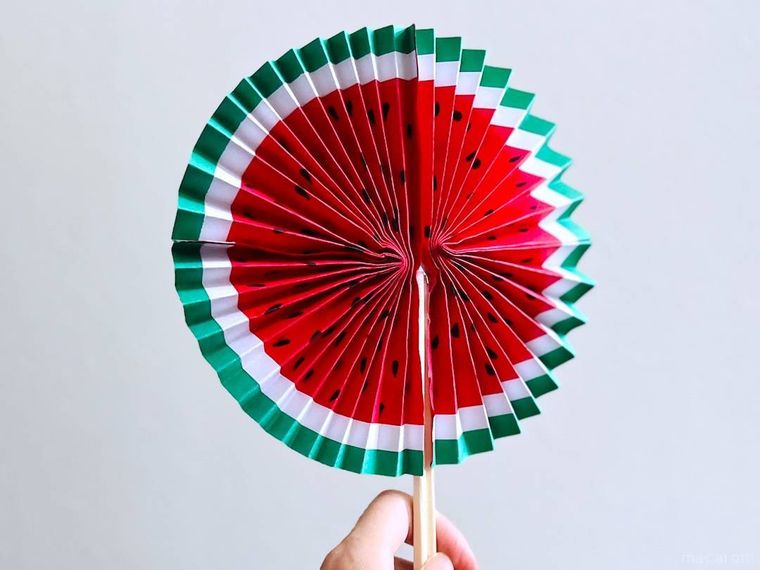 画用紙で作ったスイカ扇子を手で持っている様子