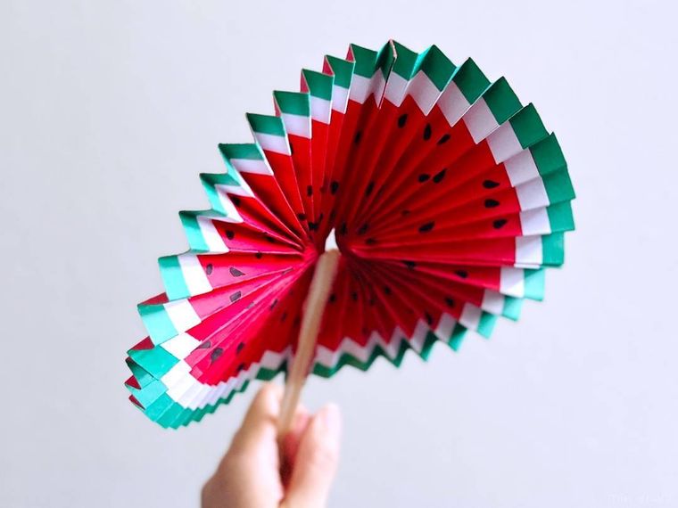 画用紙で作ったスイカ扇子をあおいでいる様子
