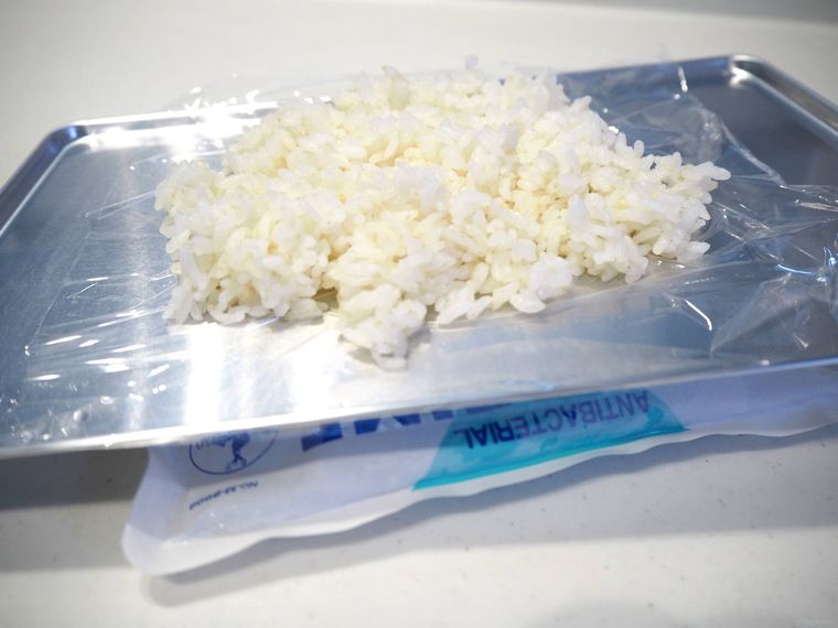 金属製のバットにのせたごはんを保冷剤で冷ましている様子