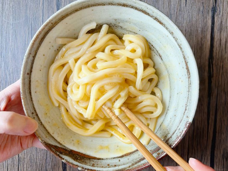 卵をうどんと混ぜる様子