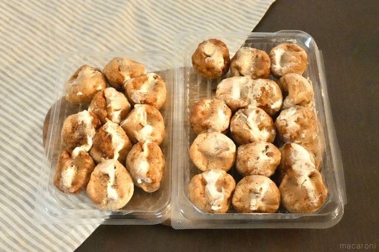 木のカッティングボードにのったたこ焼きのパック2つ
