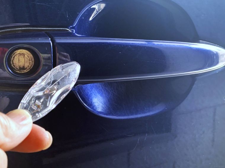 ダイソーの静電気除去キーホルダーを車のドアに当てる様子
