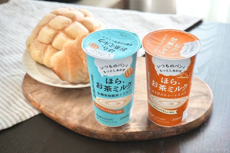 木のカッティングボードにのった水色の鉄観音烏龍茶とオレンジ色のパッケージのティー飲料と白い器に盛られたメロンパンと塩パン