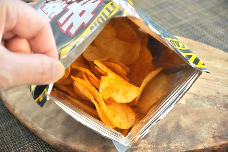 木のカッティングボードにのった激辛ポテトチップスの袋を開けた様子
