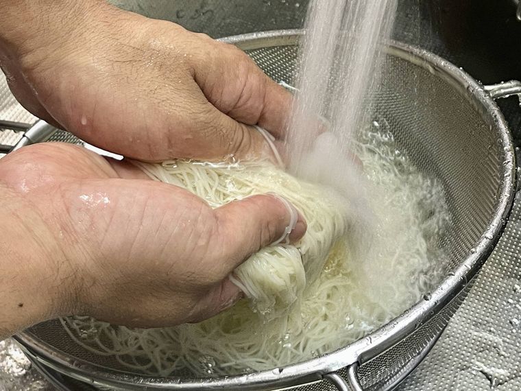 ゆでたそうめんを流水で洗う様子
