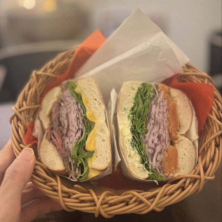 木のカゴにフルサイズのローストビーフベーグルサンドが入っている