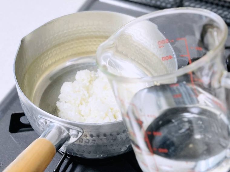 ご飯が入った鍋に水を入れようとしている様子